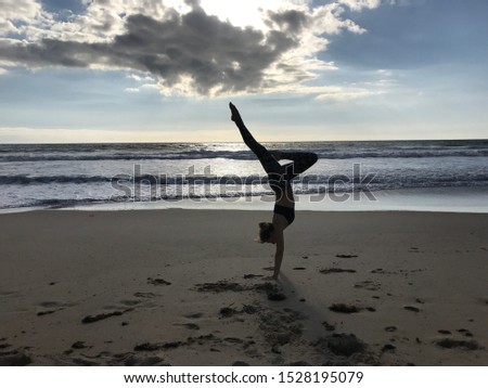 A woman with long hair dressed in sportswear practicing basic yoga postures on a sandy beach at the Mediterranean sea Estepona Andalucoia Spain. Healthy lifestyle and relax.