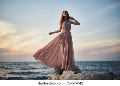 Woman In A Long Pink Dress On The Beach, Sunset.