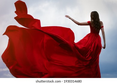 Woman In A Long Red Flying Dress. Back View
