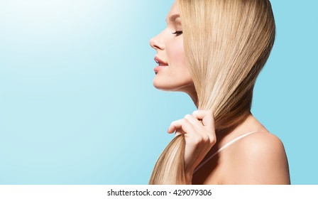 Woman With Long Thick Straight Hair In Sun On A Blue Background In Profile