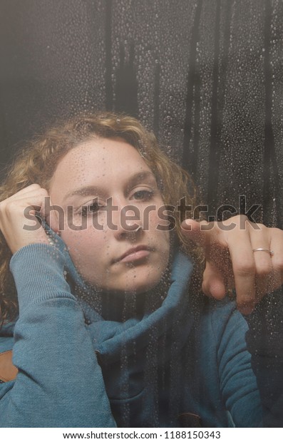 woman look through rainy\
window