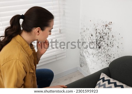 Woman looking at affected with mold walls in room