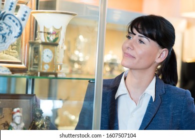 Woman Looking At Antiques In A Glass Cabinet