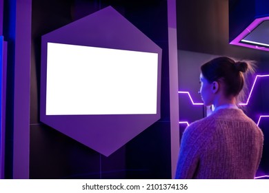 Woman Looking At Blank Digital Interactive White Display Wall At Exhibition Or Museum With Purple Futuristic Scifi Interior. White Screen, Mock Up, Future, Copyspace, Template, Technology Concept