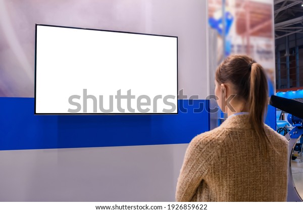 Woman looking at blank digital interactive white\
display wall at exhibition or museum with futuristic scifi\
interior. White screen, mock up, future, copyspace, template,\
technology concept