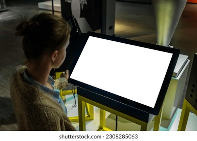Woman looking at blank white display of interactive kiosk at exhibition or museum with futuristic sci-fi interior. White screen, mockup, science, copyspace, template, technology concept - Shutterstock ID 2308285063