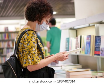 A Woman Looking At Books In A Bookstore Wears A Face Mask That Protects Her From Viruses