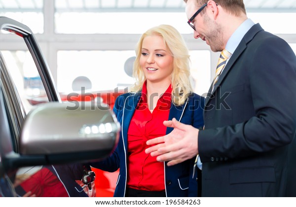 Woman looking at car in\
auto dealership