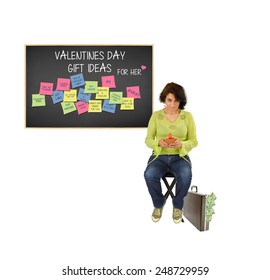 Woman Looking Up From Cell Phone Briefcase Money Overflowing Behind Blackboard With Valentines Day Gift Ideas For Her (box Of Chocolate, Engagement Ring, Spa, Trip, Lingerie, Dinner, Movie And More) 