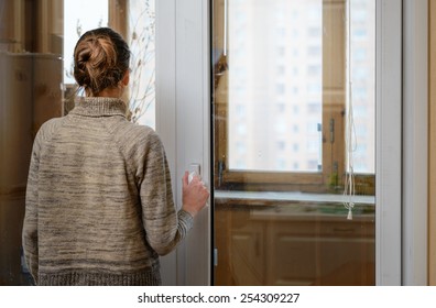 A Woman Is Looking The City Through The Window During A Sad Winter Day