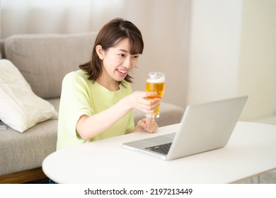 Woman Looking At Computer While Drinking Beer