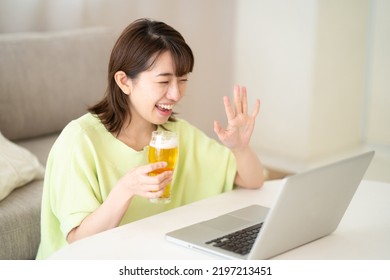 Woman Looking At Computer While Drinking Beer