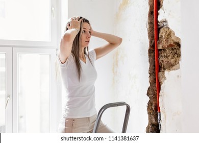 Woman Looking At Damage After A Water Pipe Leak At Home