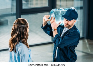 Woman Looking At Delivery Man Holding Water Bottle