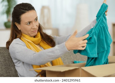 woman looking with disdain at a top delivered by courrier