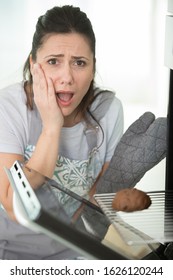 Woman Looking With Dismay At Burnt Food In The Oven