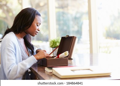 Woman Looking At Document In Keepsake Box On Desk