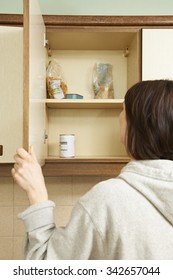 Woman Looking In Empty Food Cupboards