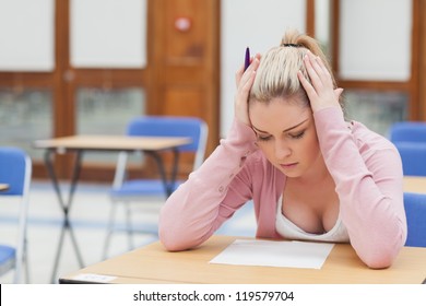 Woman looking at exam paper anxiously in exam hall