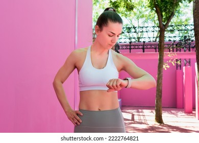 Woman looking at fitness trackers into workout routine outside. Smart watch for figure out current heart rate zone during exercise. Active, healthy lifestyle concept.