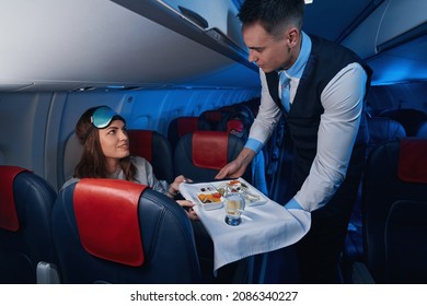 Woman looking at flight steward while taking her meal - Shutterstock ID 2086340227