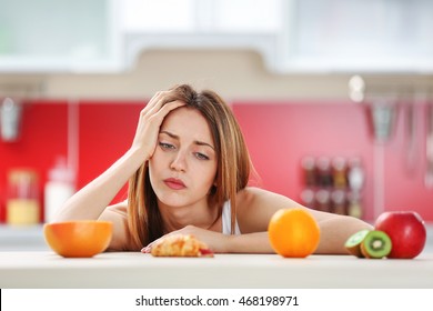 Woman Looking Guilty At Croissant Lying Among Fruits