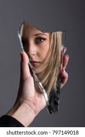 Woman Looking At Her Face In A Shard Of Broken Mirror