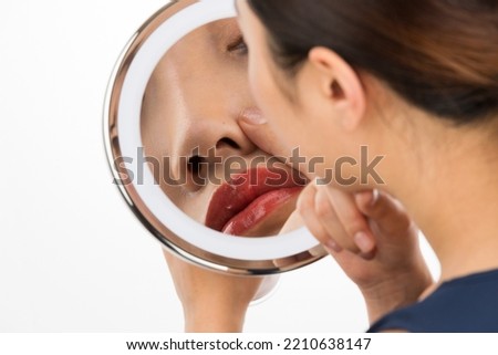 A woman looking at her nose in the mirror.