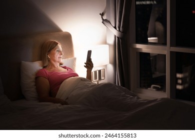 Woman looking at her phone at big window with city view. Female enjoying calm quiet time with social media. People read and relax. Modern apartment in high rise building. - Powered by Shutterstock