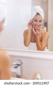 Woman looking herself reflection in mirror after the shower 
