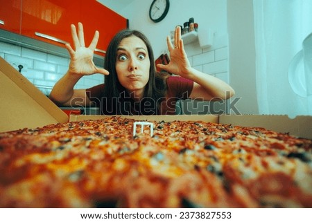 
Woman Looking at the Huge Mind-Blowing Pizza She Ordered. Hungry girl eating a fast food for comfort at home
