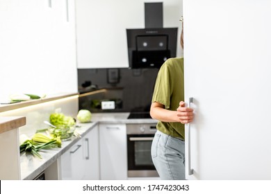 Woman looking into the fridge while cooking healthy food on the modern kitchen at home
