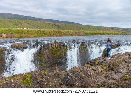 A woman looking at Kolufoss waterfall at Kolugljufur canyon on Iceland