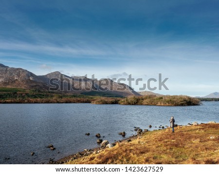 Woman looking at landscape, Derryclare lake, Connemara National park, Ireland, Blue cloudy sky, mountains.