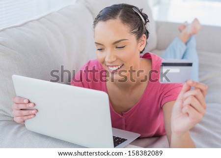 Woman looking at a laptop and holding a credit card at home