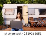 Woman looking at the laptop near the camping . Caravan car Vacation. Family vacation travel, holiday trip in motorhome RV. Wi-fi connection information communication technology.