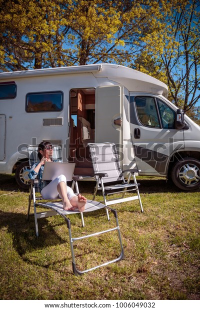 Woman
looking at the laptop near the camping . Caravan car Vacation.
Family vacation travel, holiday trip in motorhome RV. Wi-fi
connection information communication
technology.