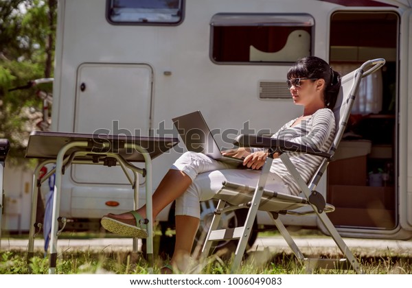 Woman
looking at the laptop near the camping . Caravan car Vacation.
Family vacation travel, holiday trip in motorhome RV. Wi-fi
connection information communication
technology.