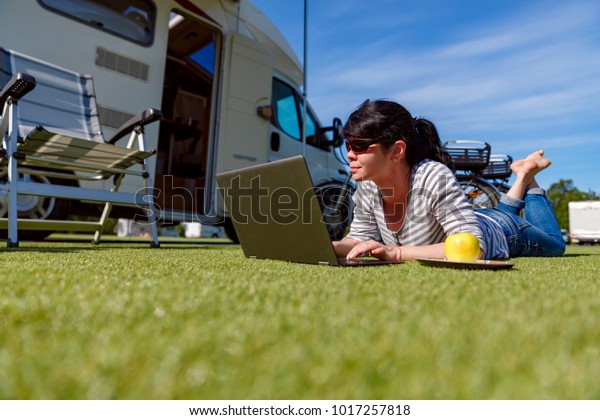 Woman\
looking at the laptop near the camping . Caravan car Vacation.\
Family vacation travel, holiday trip in motorhome RV. Wi-fi\
connection information communication\
technology.