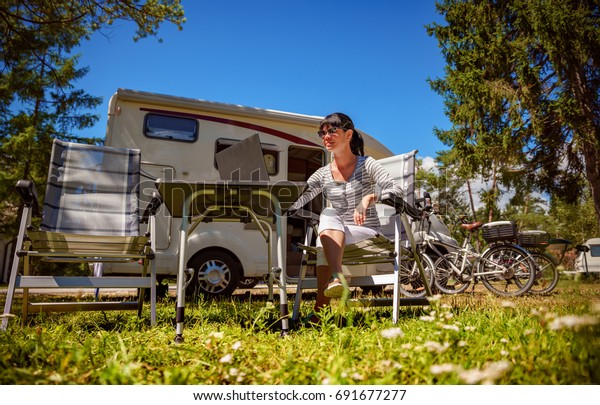 Woman looking at\
the laptop near the camping . Caravan car Vacation. Family vacation\
travel, holiday trip in motorhome. Wi-fi connection information\
communication technology.