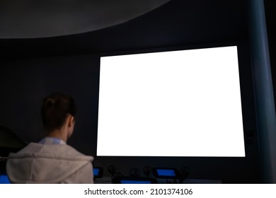 Woman Looking At Large Wall Blank Interactive White Display In Dark Room Of Modern Technology Exhibition, Museum Or Cinema. Mock Up, White Screen, Futuristic, Template, Education Concept