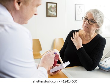 Woman Looking At Male Doctor Explaining Shoulder Rotator Cuff Mo