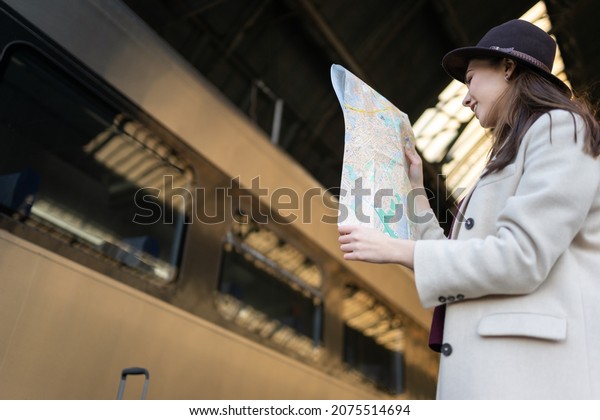 Woman looking at the map standing on the\
platform of the railway station. Travel\
concept	