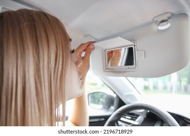 Woman Looking In The Mirror In The Car Sun Visor