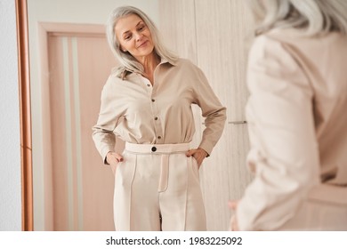Woman looking at the mirror at her reflection while trying on new clothes
