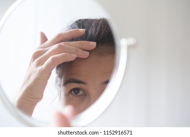 Woman Is Looking At The Mirror To See Her Hair Loss Problem. Gray Hair Problem For Middle Ages Woman