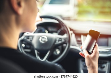 Woman looking at mobile phone while driving a car. Transportation and vehicle concept. - Shutterstock ID 1789744820