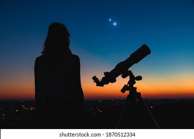 Woman Looking At Night Sky With Amateur Astronomical Telescope.