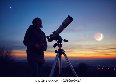 Woman Looking At Night Sky With Amateur Astronomical Telescope.