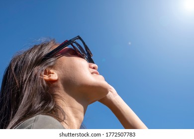 Woman Is Looking On Solar Eclipse Through Three Sunglasses. Sun Eclipse Concept.